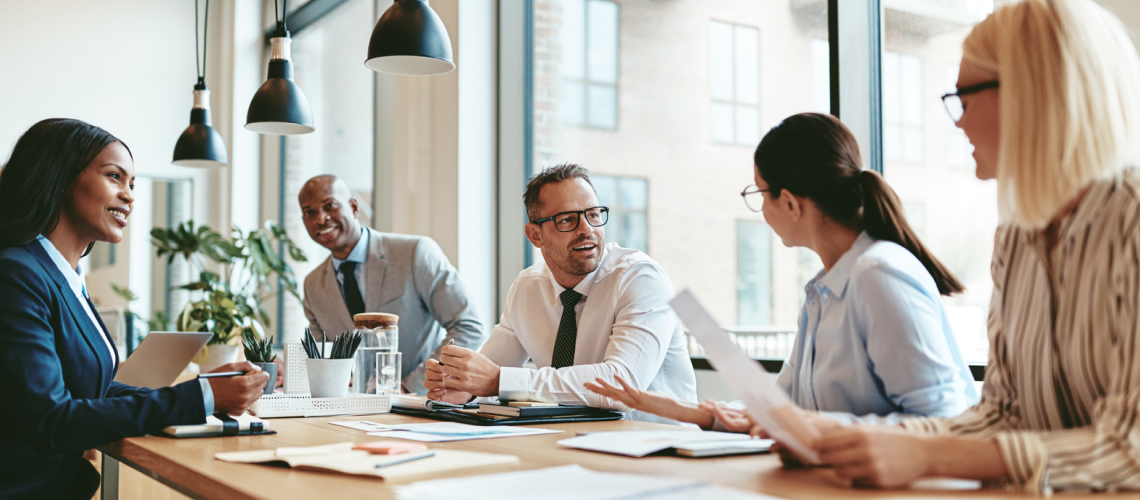 A group of professionals in conversation at a meeting table